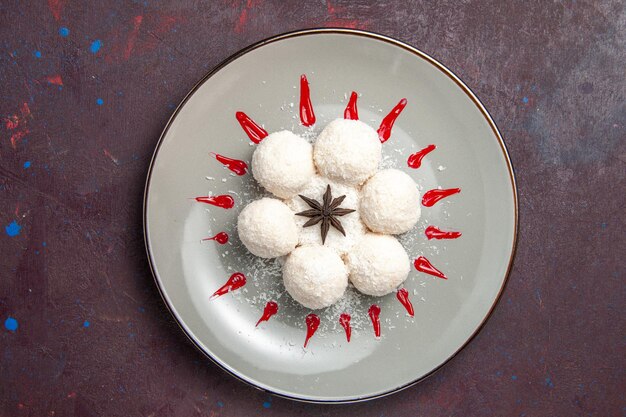 Vista superior de deliciosos caramelos de coco con glaseados rojos sobre negro