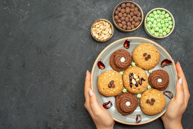 Vista superior de deliciosos caramelos con pequeñas galletas en el espacio oscuro