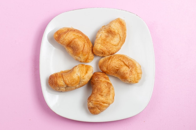 Vista superior deliciosos croissants horneados con relleno de frutas en el interior del escritorio rosa