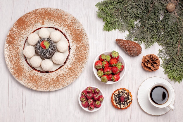 Vista superior de deliciosos dulces de coco con té de pastel y frutas en blanco