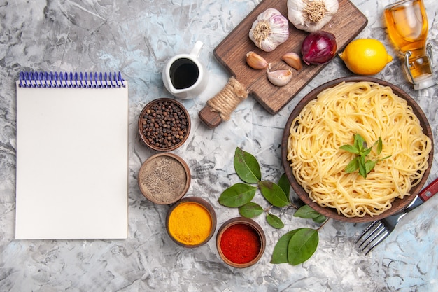 Vista superior deliciosos espaguetis con condimentos en la masa de pasta de comida de mesa blanca