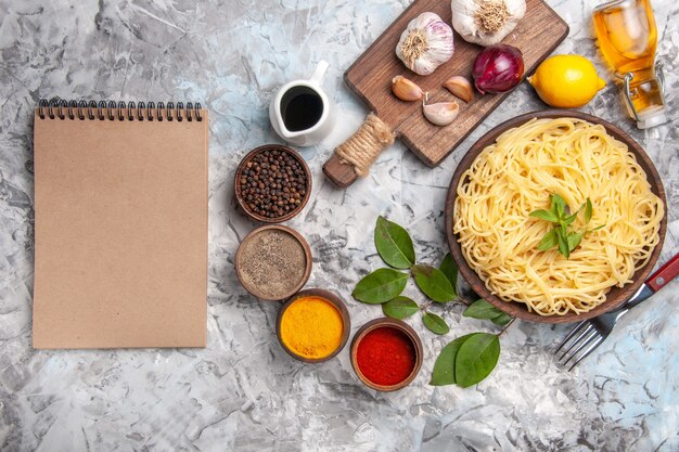 Vista superior deliciosos espaguetis con condimentos en el piso blanco color de masa de pasta de comida