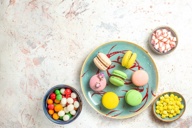 Vista superior deliciosos macarons franceses con caramelos en galleta de pastel dulce blanco