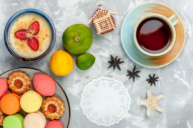 Vista superior deliciosos macarons franceses con postre de galletas y té sobre fondo blanco claro hornear pastel galleta azúcar dulce