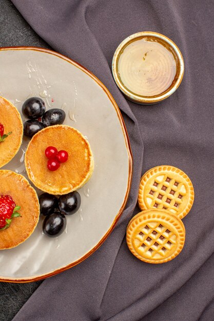 Vista superior deliciosos panqueques con aceitunas y frutas en la oscuridad