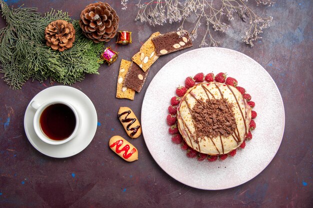 Vista superior de deliciosos panqueques afrutados con taza de té en la oscuridad