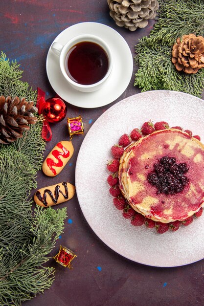 Vista superior de deliciosos panqueques afrutados con taza de té en la oscuridad