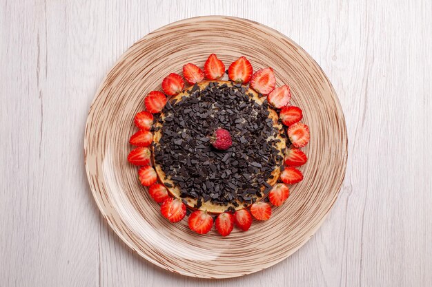 Vista superior de deliciosos panqueques al horno con fresas y chispas de chocolate en la mesa blanca