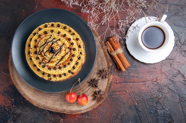 Vista superior deliciosos panqueques dulces con taza de té en superficie oscura