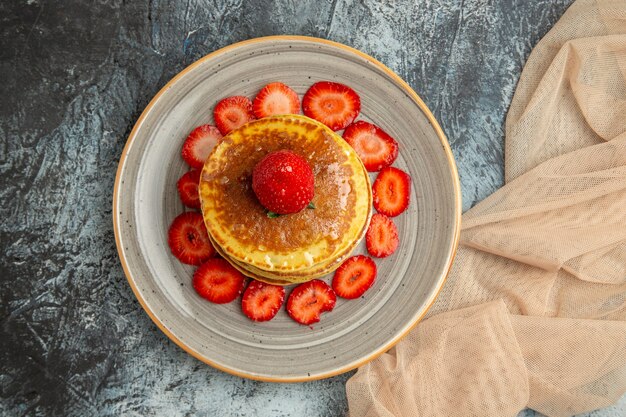 Vista superior deliciosos panqueques con fresas frescas a la luz