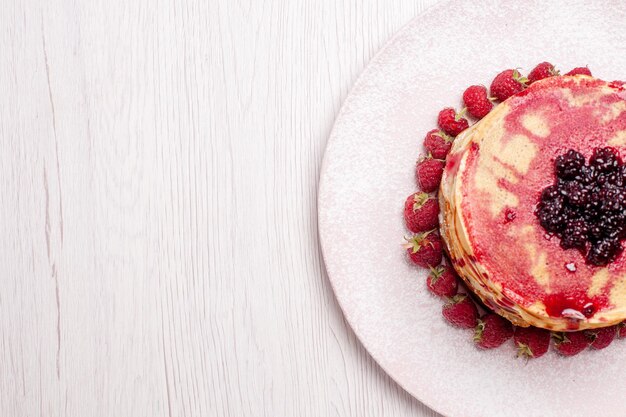 Vista superior deliciosos panqueques con fresas y gelatina en el escritorio blanco pastel pastel galleta baya dulce