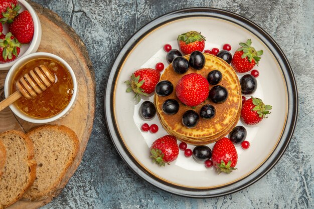 Vista superior deliciosos panqueques con frutas frescas y pan en piso ligero pastel de frutas dulce