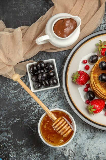 Vista superior deliciosos panqueques con frutas y miel en la superficie de luz pastel de frutas dulces