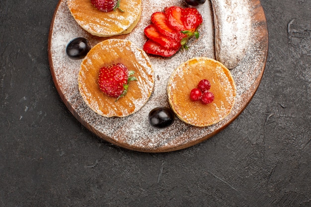 Foto gratuita vista superior deliciosos panqueques con frutas y pasteles en la oscuridad