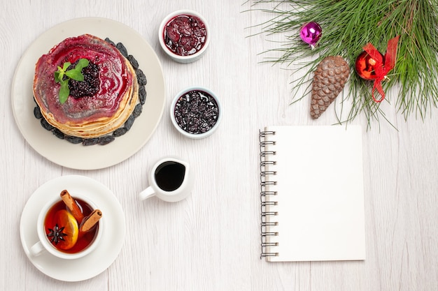 Vista superior deliciosos panqueques de gelatina con jalea afrutada de pasas y taza de té en blanco