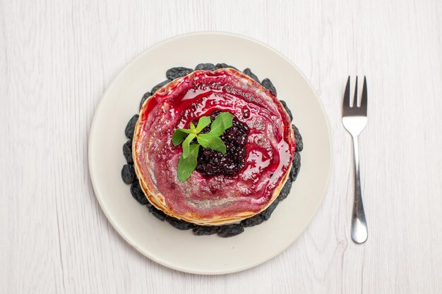 Vista superior deliciosos panqueques de gelatina con pasas y gelatina de frutas sobre fondo blanco mermelada de postre de galleta de gelatina dulce