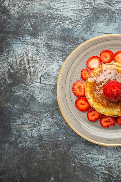 Vista superior deliciosos panqueques con miel y fresas a la luz