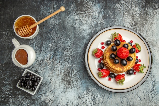 Vista superior deliciosos panqueques con miel y frutas en mesa de luz pastel de frutas dulce