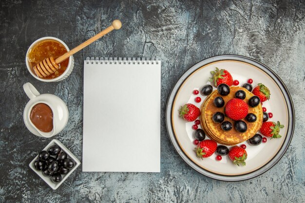 Vista superior deliciosos panqueques con miel y frutas en piso ligero pastel de frutas dulce