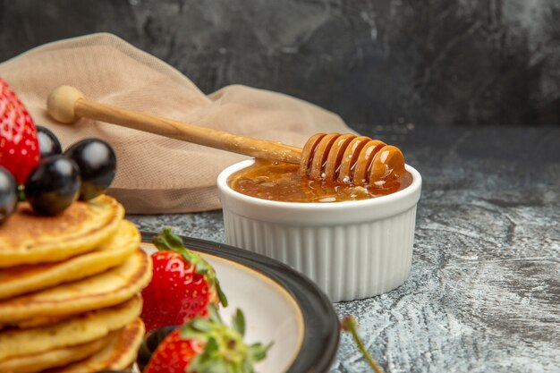 Vista superior de deliciosos panqueques con miel y frutas sobre una superficie ligera pastel dulce frutas