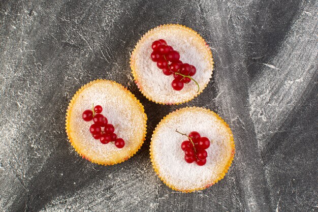 Vista superior deliciosos pasteles de arándanos horneados y deliciosos con arándanos rojos en la parte superior fondo gris pastel galleta azúcar dulce hornear