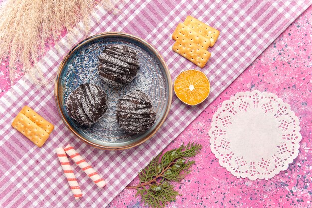 Vista superior de deliciosos pasteles de chocolate con galletas en rosa