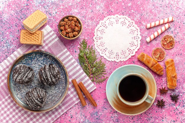 Vista superior deliciosos pasteles de chocolate con taza de té en rosa claro