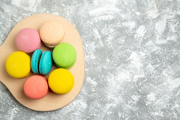 Vista superior deliciosos pasteles coloridos macarons franceses en el escritorio blanco