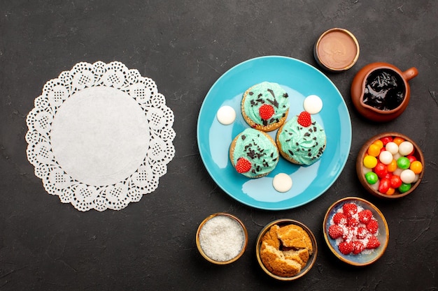 Vista superior deliciosos pasteles cremosos con caramelos sobre fondo oscuro pastel de galleta postre dulces galletas color