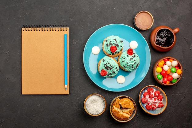 Foto gratuita vista superior deliciosos pasteles cremosos con caramelos sobre fondo oscuro pastel de galletas dulces postre galletas color