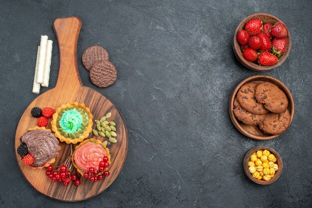 Vista superior deliciosos pasteles cremosos con galletas en el postre dulce de galletas de mesa oscura