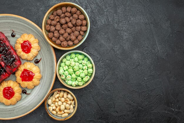 Vista superior de deliciosos pasteles, dulces afrutados con galletas y caramelos sobre fondo oscuro, galletas de azúcar, pastel de galletas, pastel dulce