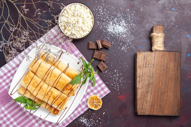 Vista superior de deliciosos pasteles dulces con chocolate y requesón en el espacio oscuro