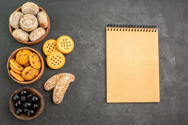 Foto gratuita vista superior de deliciosos pasteles dulces con galletas y aceitunas en pasteles de superficie oscura pastel dulce