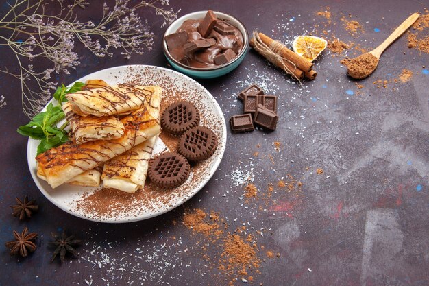 Vista superior de deliciosos pasteles dulces con galletas de chocolate en el espacio oscuro