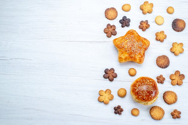 Vista superior de deliciosos pasteles dulces con galletas en el escritorio ligero, pastelería galleta galleta azúcar dulce