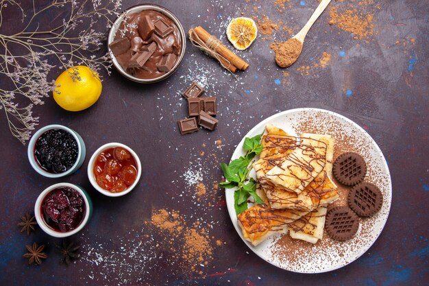 Vista superior deliciosos pasteles dulces con galletas y mermelada sobre fondo oscuro galleta galleta azúcar té dulce pastel