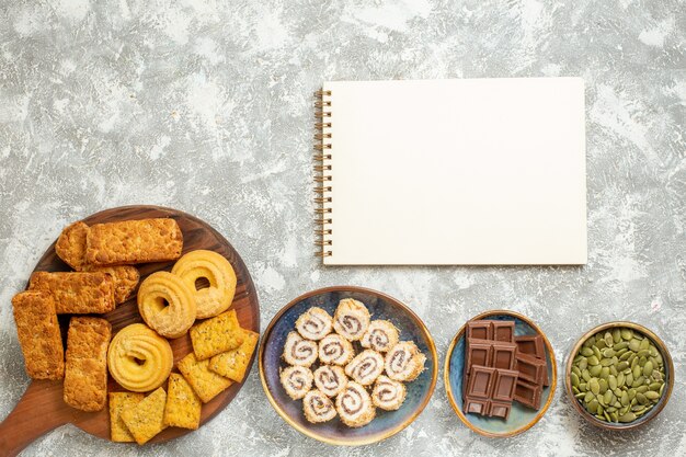 Vista superior de deliciosos pasteles con dulces y galletas sobre fondo blanco claro