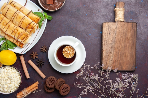 Foto gratuita vista superior de deliciosos pasteles dulces con galletas y té en el espacio oscuro