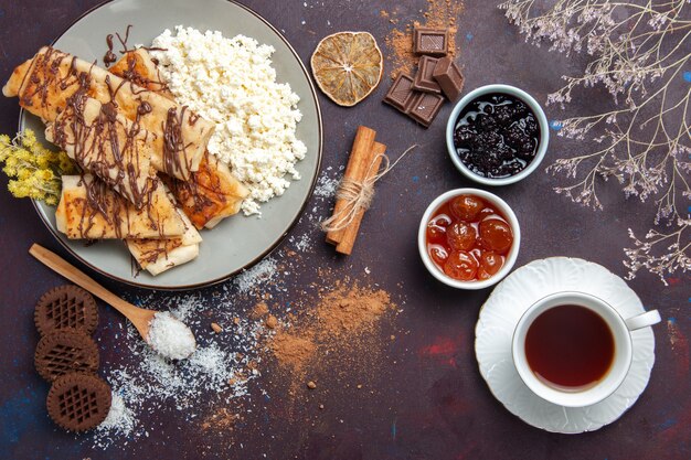 Vista superior deliciosos pasteles dulces con té de requesón y galletas sobre fondo oscuro galleta galleta azúcar pastel dulce té