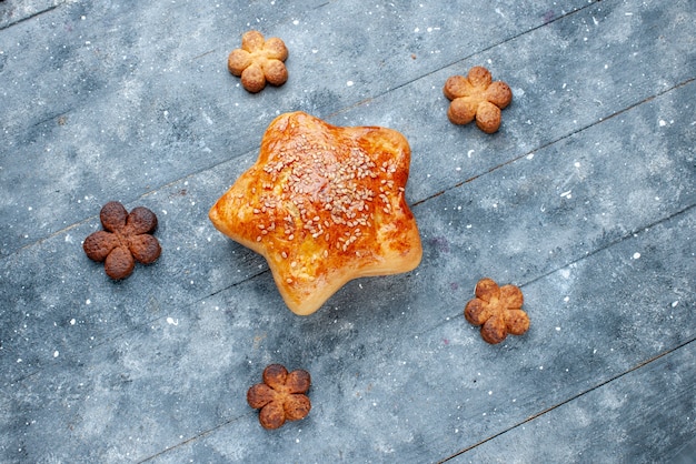 Vista superior de deliciosos pasteles en forma de estrella con galletas en el escritorio gris, pastel de azúcar de pastelería dulce