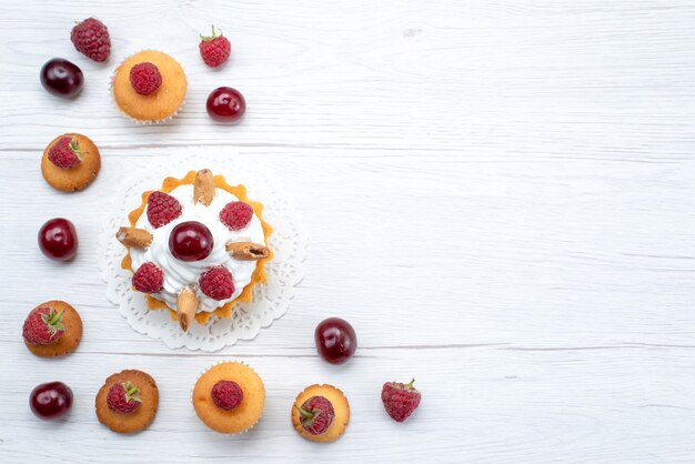 Vista superior deliciosos pasteles con frambuesas junto con galletas y pasteles en la mesa de luz pastel galleta baya dulce hornear fruta