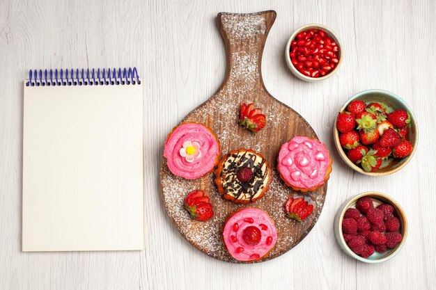 Vista superior de deliciosos pasteles de frutas, postres cremosos con bayas y frutas sobre un fondo blanco crema dulce postre pastel de galletas té