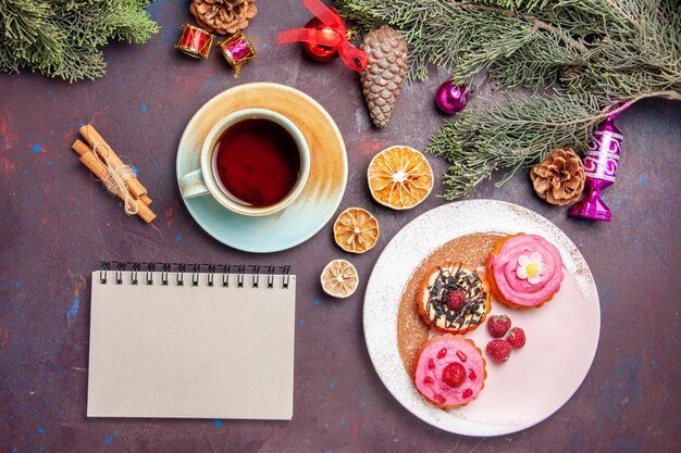 Vista superior de deliciosos pasteles con frutas y taza de té en negro