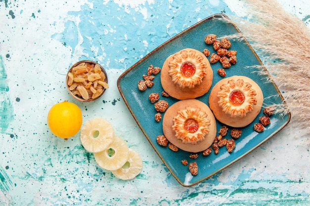 Vista superior de deliciosos pasteles con galletas y nueces dulces en el escritorio azul claro hornear pastel de galletas nuez de azúcar dulce