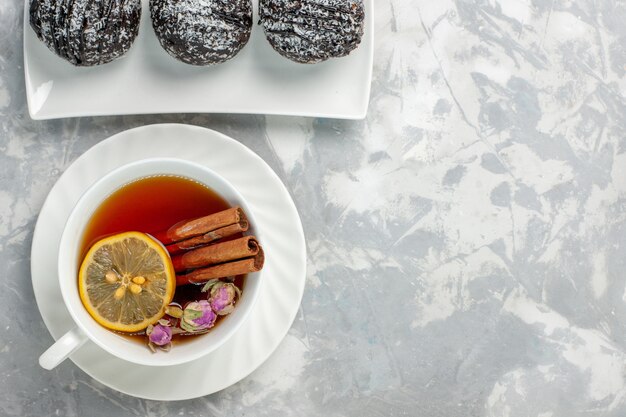 Vista superior deliciosos pasteles con glaseado y una taza de té en el fondo blanco claro pastel de galletas de té hornear pastel dulce de azúcar