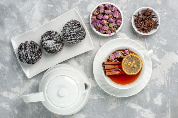 Vista superior de deliciosos pasteles con glaseado y una taza de té en la superficie de color blanco claro pastel de galletas de té hornear azúcar dulce pastel