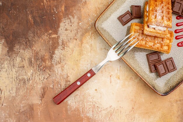 Foto gratuita vista superior deliciosos pasteles de gofres con barras de chocolate en el fondo marrón