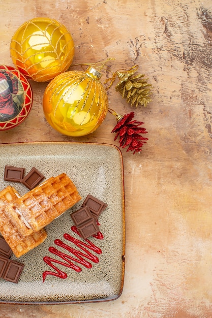 Foto gratuita vista superior deliciosos pasteles de gofres con chocolate y juguetes de árbol de año nuevo en el fondo claro