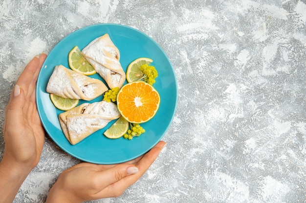 Vista superior de deliciosos pasteles de masa con rodajas de limón sobre fondo blanco pastelería azúcar hornear masa de pastel dulce pastel de galleta